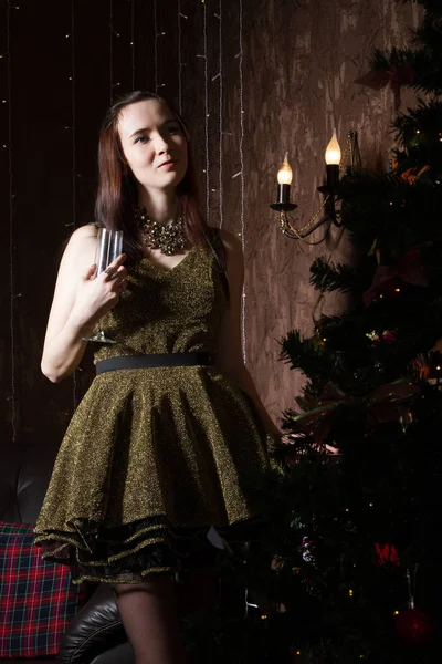 Schlanke junge Frau im kurzen Kleid steht neben einem Weihnachtsbaum — Stockfoto