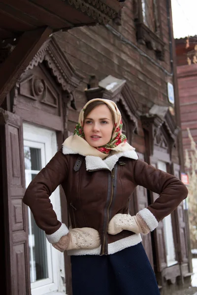 Girl in a scarf on the background of an old wooden house — Stock Photo, Image