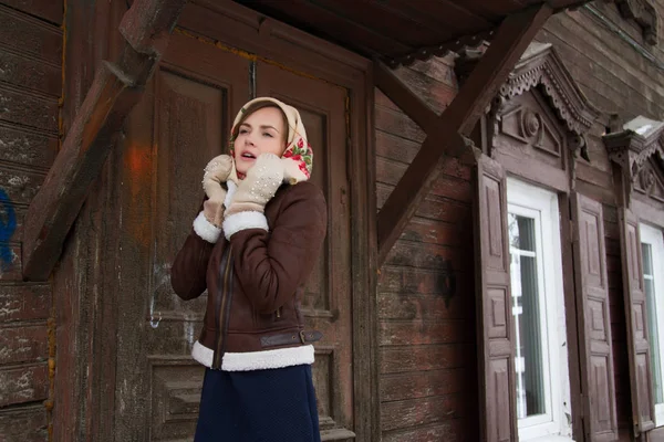 Girl in a scarf on the background of an old wooden house — Stock Photo, Image