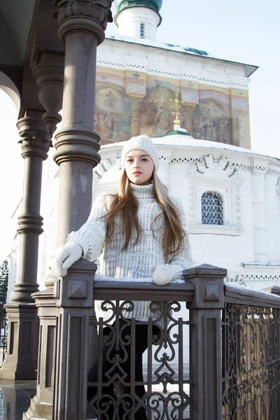 Young girl in a sweater and knit hat on the background of the church. Winter portrait — Stock Photo, Image