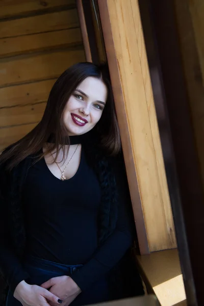 Chica de pie en la ventana en una habitación con paredes de madera —  Fotos de Stock