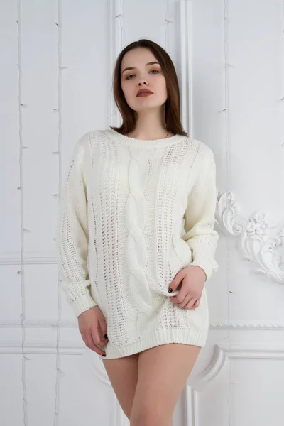 Belle jeune fille dans un pull blanc sur le mur de fond avec stuc — Photo