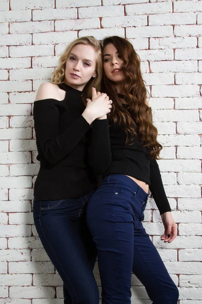 Brunette and the blonde on the background of brick wall — Stock Photo, Image