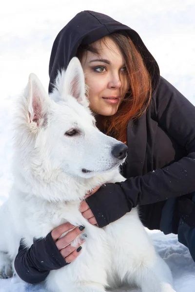 Κορίτσι με ένα λευκό σκυλί ποιμένων ξαπλωμένη στο χιόνι — Φωτογραφία Αρχείου