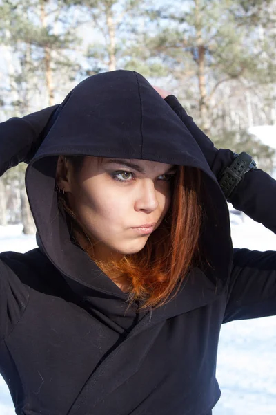 Chica en el capó en el fondo del parque cubierto de nieve —  Fotos de Stock