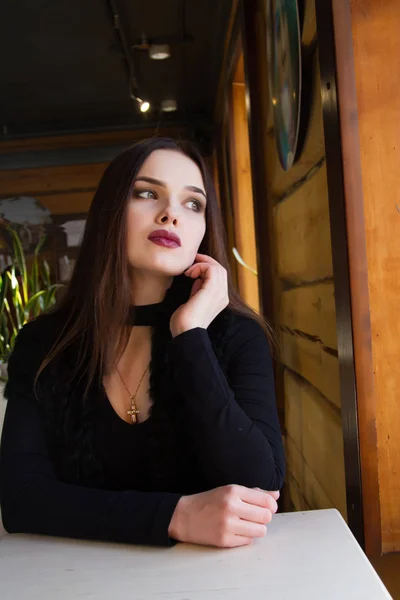 Chica romántica sentada en una mesa junto a la ventana — Foto de Stock