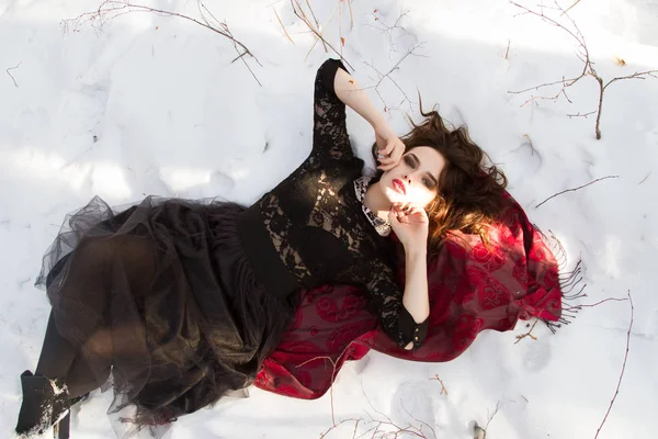 Junges Mädchen liegt im Schnee im Winterwald — Stockfoto