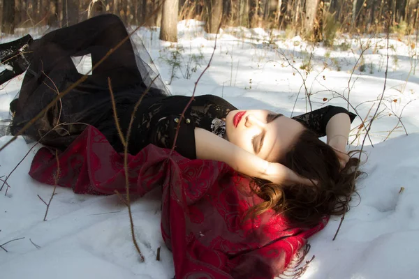 Νέο κορίτσι ξαπλωμένο στο χιόνι μέσα στο δάσος του χειμώνα — Φωτογραφία Αρχείου