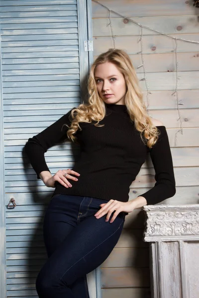 Blonde with long hair standing by the fireplace — Stock Photo, Image