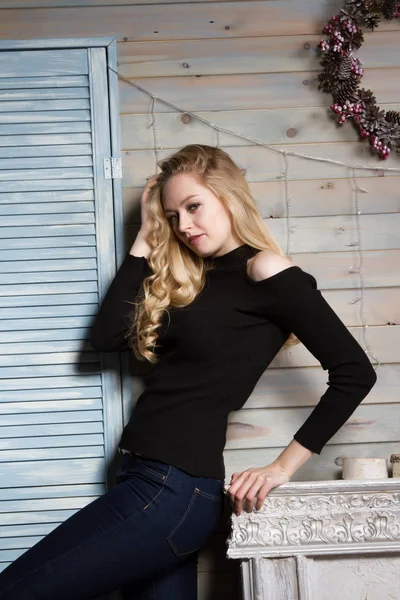 Blonde with long hair standing by the fireplace — Stock Photo, Image