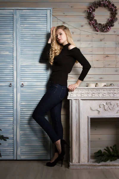 Blonde with long hair standing by the fireplace — Stock Photo, Image