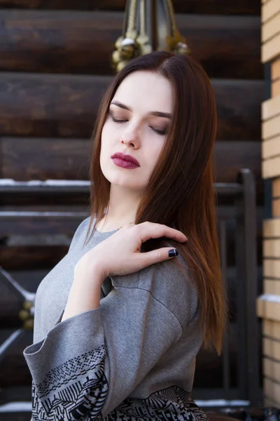 Chica en un suéter en el fondo de una pared de troncos — Foto de Stock