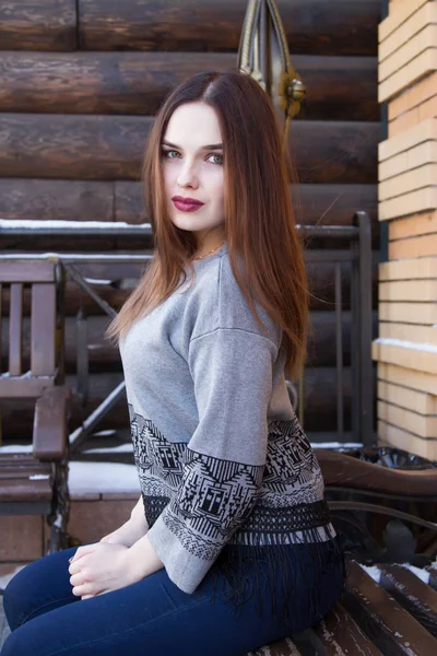 Chica en un suéter en el fondo de una pared de troncos — Foto de Stock