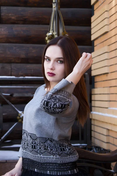 Menina em uma camisola no fundo de uma parede de log — Fotografia de Stock