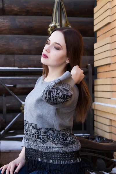 Chica en un suéter en el fondo de una pared de troncos — Foto de Stock