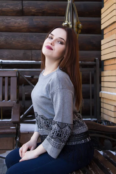 Chica en un suéter en el fondo de una pared de troncos — Foto de Stock