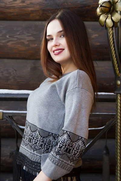 Girl in a sweater on the background of a log wall — Stock Photo, Image