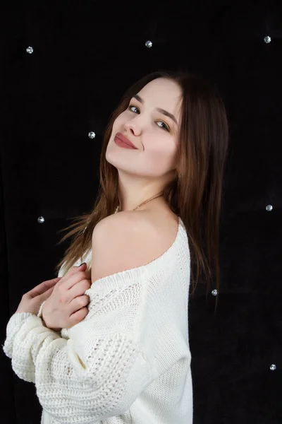 Retrato de una chica emocional en un suéter blanco sobre un fondo negro. Retrato de estudio — Foto de Stock