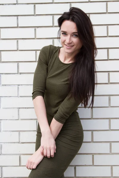 Chica joven en un vestido sobre un fondo de pared de ladrillo — Foto de Stock