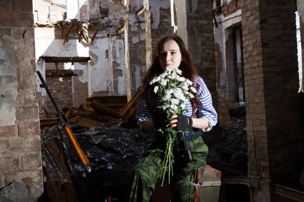 Flicka sniper på ruinerna med en bukett blommor — Stockfoto