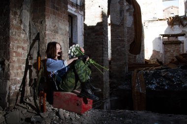 Bir buket çiçek ile yıkıntıları üzerinde kız keskin nişancı