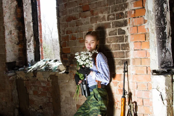Niña francotirador en las ruinas con un ramo de flores — Foto de Stock