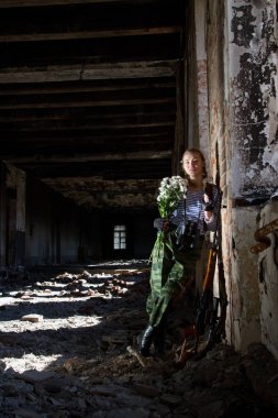keskin nişancı kız chamomiles bir buket ile harap bir bina duruyor