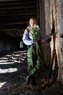 keskin nişancı kız chamomiles bir buket ile harap bir bina duruyor