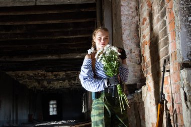 keskin nişancı kız chamomiles bir buket ile harap bir bina duruyor