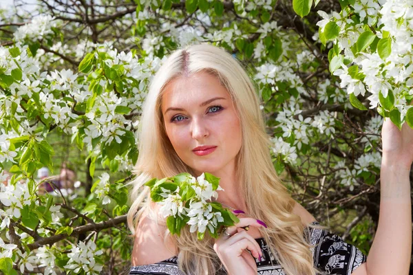 Jeune blonde en arrière-plan de pommiers en fleurs dans le jardin — Photo