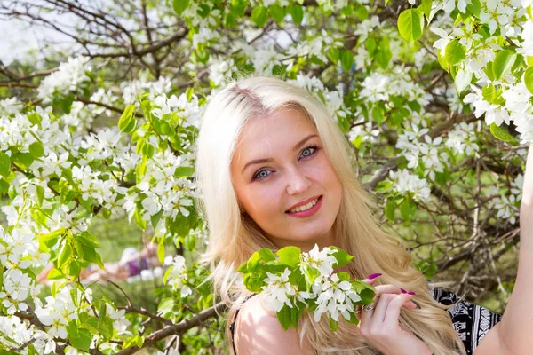 Mladá blondýnka v pozadí rozkvetlé jabloně v zahradě — Stock fotografie