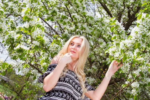 Junge Blondine im Hintergrund blühender Apfelbäume im Garten — Stockfoto