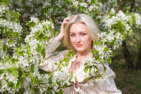 Young blonde in the background of blossoming apple trees in the garden — Stock Photo, Image