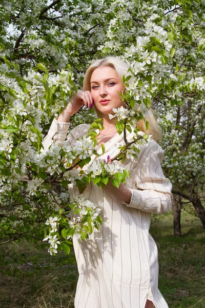 Jeune blonde en arrière-plan de pommiers en fleurs dans le jardin — Photo