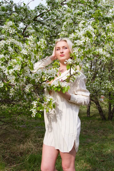 Genç kız bahçede çiçek açan elma ağaçlarının arka planı beyaz şapkalı — Stok fotoğraf