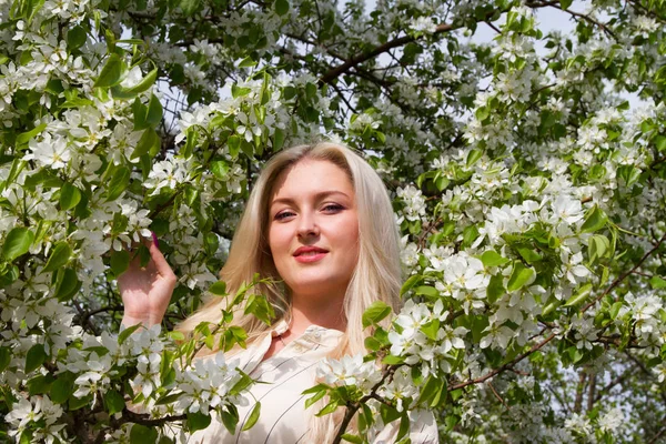 Young girl on the background of blossoming apple trees in the garden — Stock Photo, Image