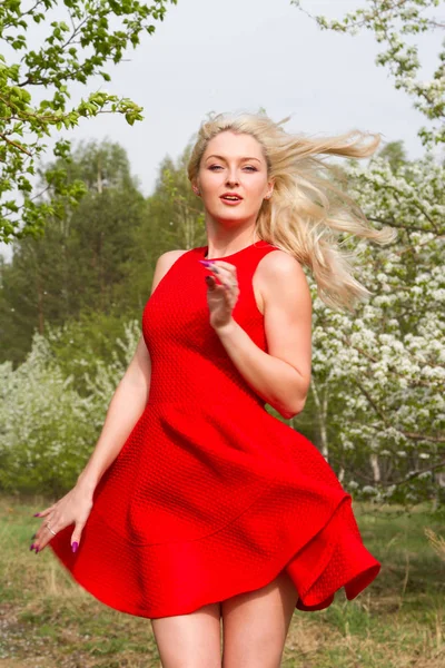 Niña en un vestido corto aleteo contra el telón de fondo de un jardín floreciente —  Fotos de Stock