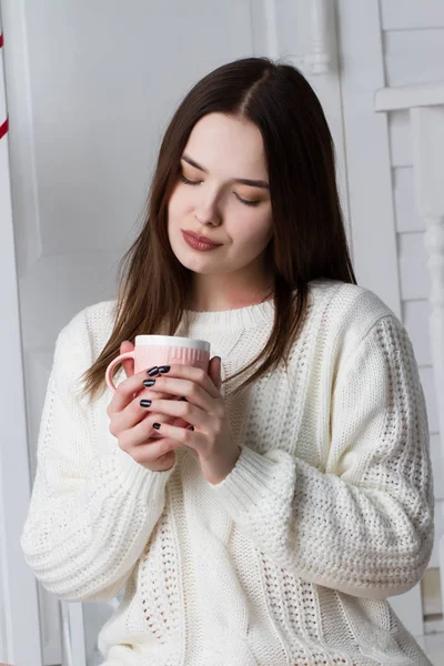 Chica joven emocional en un suéter blanco con una taza de té — Foto de Stock