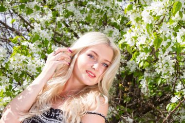 Genç sarışın bir bahçe çiçekli ağaçlar bir arka plan üzerinde