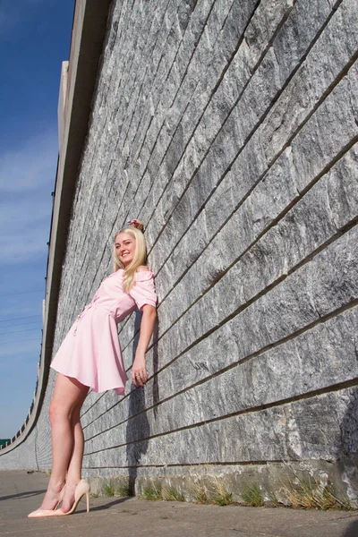 Jeune fille dans une robe rose près d'un mur de granit — Photo