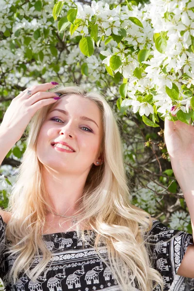 Jeune blonde dans un jardin sur fond d'arbres à fleurs — Photo