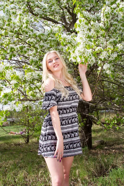 Mladá blondýnka v zahradě na pozadí kvetoucích stromů — Stock fotografie