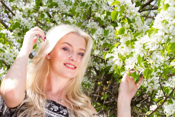 Jeune blonde dans un jardin sur fond d'arbres à fleurs — Photo