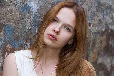 Eski püskü bir duvar arka plan üzerinde elbiseli kızıl saçlı kız