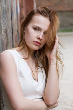 Eski püskü bir duvar arka plan üzerinde elbiseli kızıl saçlı kız