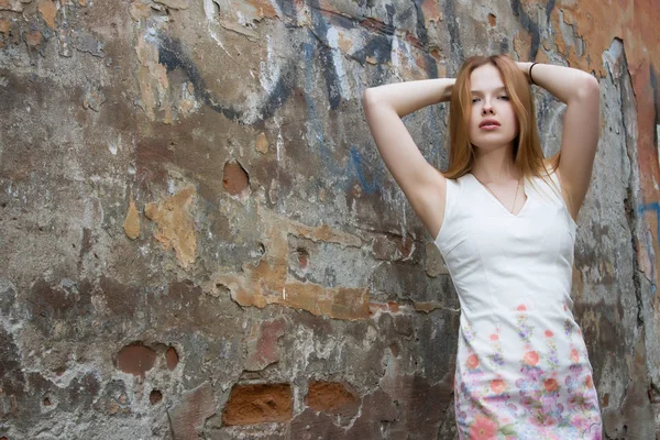 Rusovlasá dívka v šatech na pozadí omšelé zdi — Stock fotografie