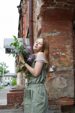 Kırmızı saçlı kız leylak bir buket tutuyor