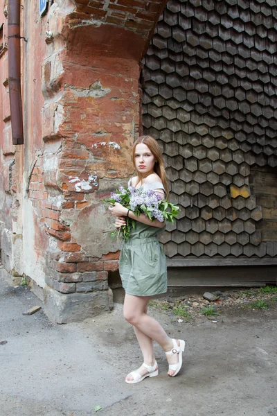 Girl with red hair is holding a bouquet of lilacs — Stock Photo, Image