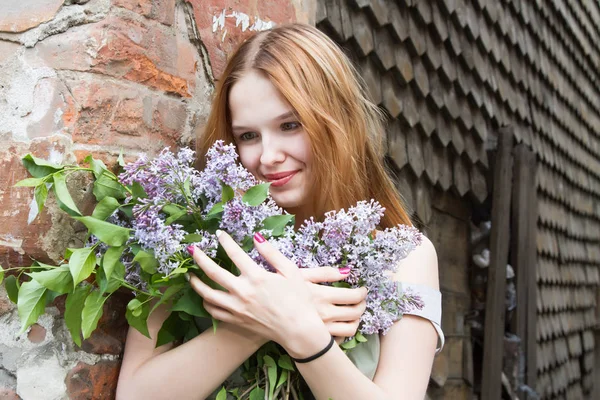 Ragazza con i capelli rossi sta tenendo un mazzo di lilla — Foto Stock