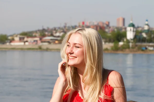 Blonde is permanent door het hek aan de kade van de rivier — Stockfoto